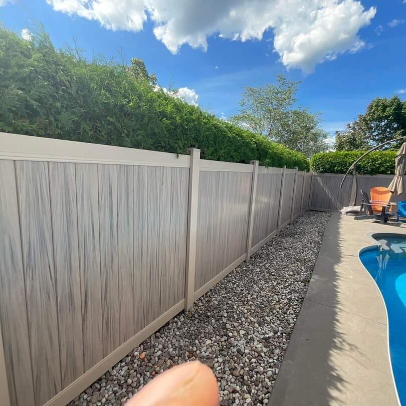 s1 Backyard fence beside pool under blue sky.